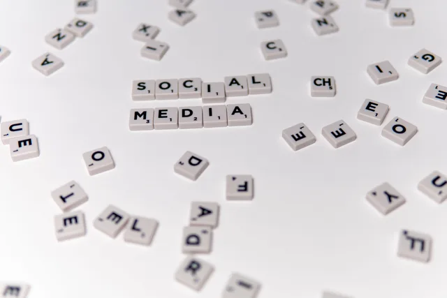 White Scrabble tiles forming the phrase 'social media' on a scattered background. Social media training software selection: test one task
