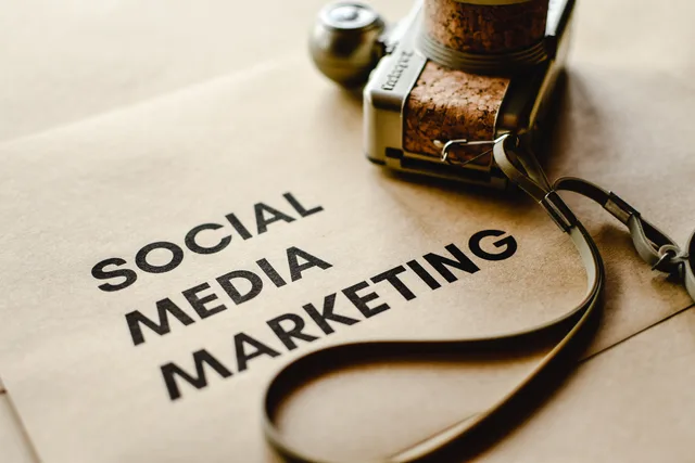 Close-up of a camera placed on brown paper with 'Social Media Marketing' text, emphasizing digital marketing themes. Six social media training strategy mistakes, from buying content early to live-account practice