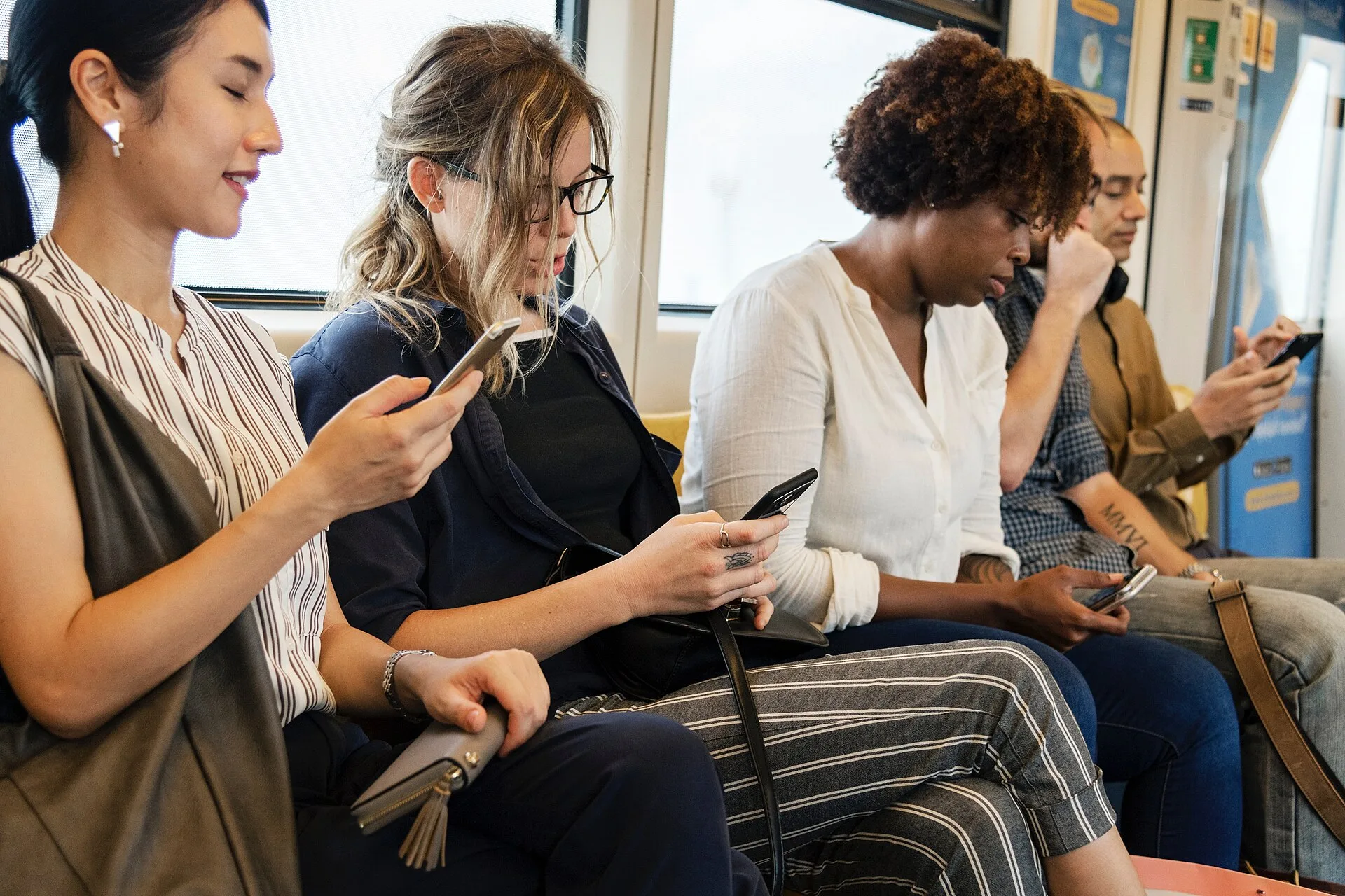 A group of diverse people using smartphones in public.